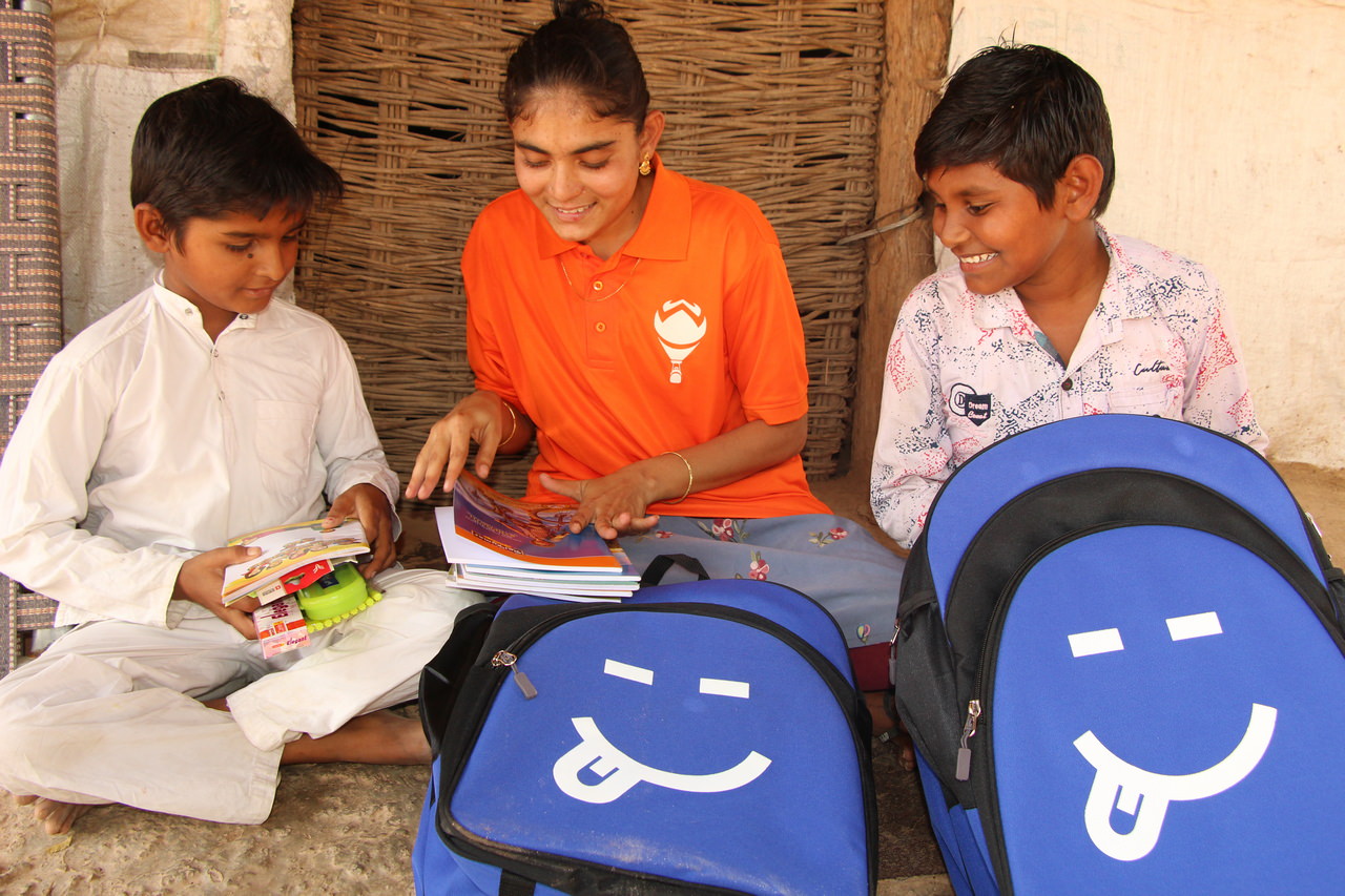 A Hope Carrier volunteer shows two boys lessons included in their school bags