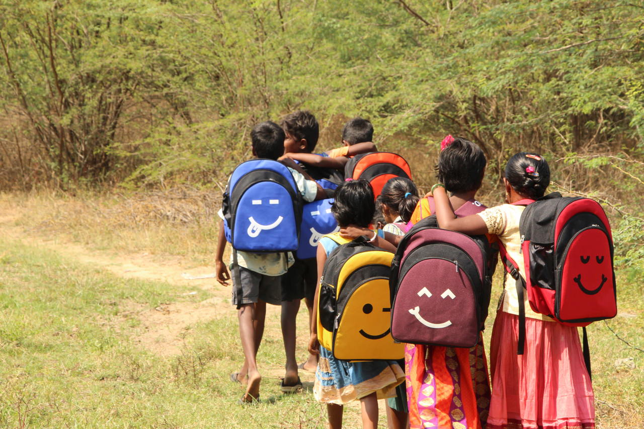 A small group of children walk home after receiving their backpacks