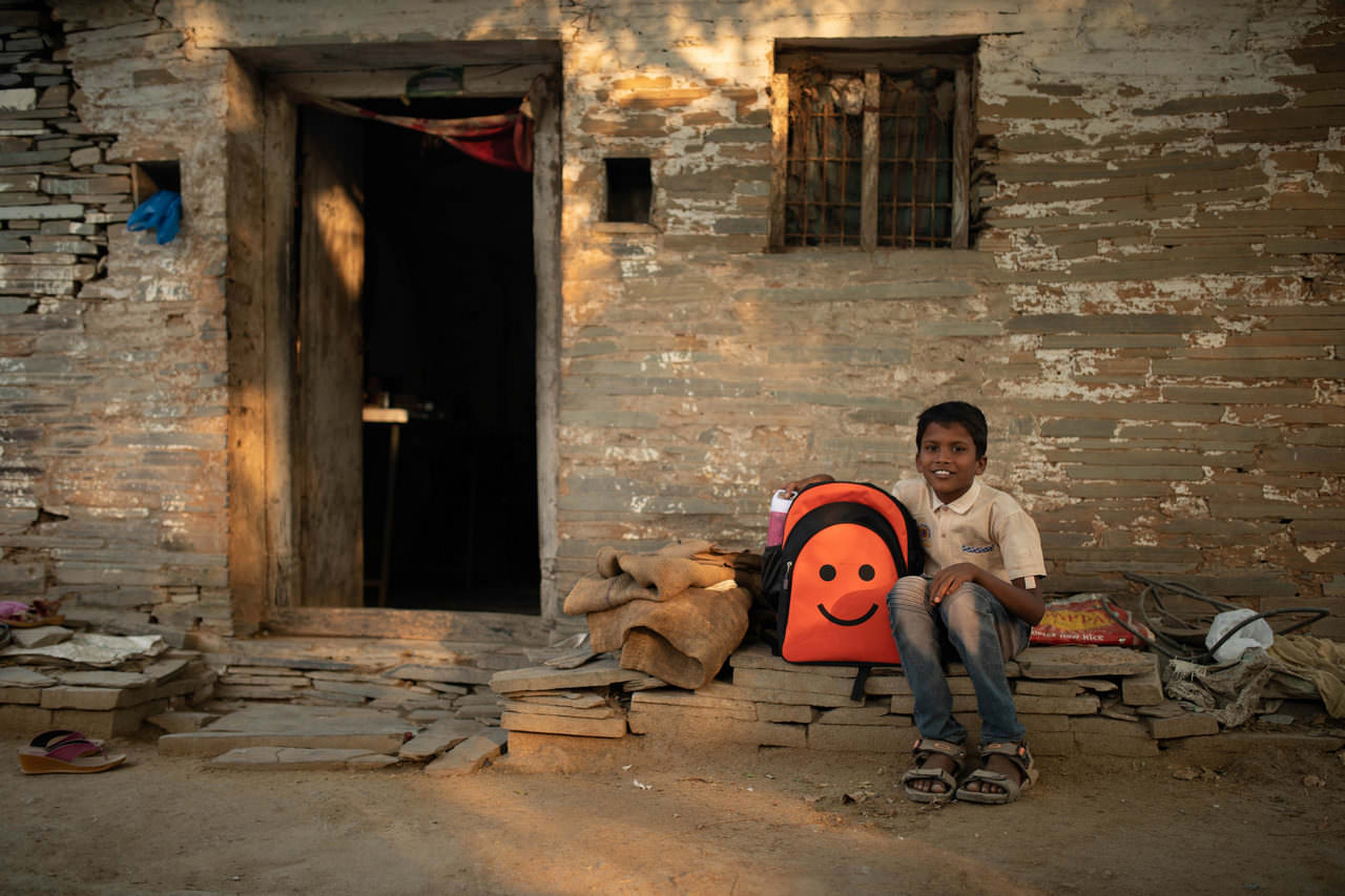 A boy poses for a photo outside his home
